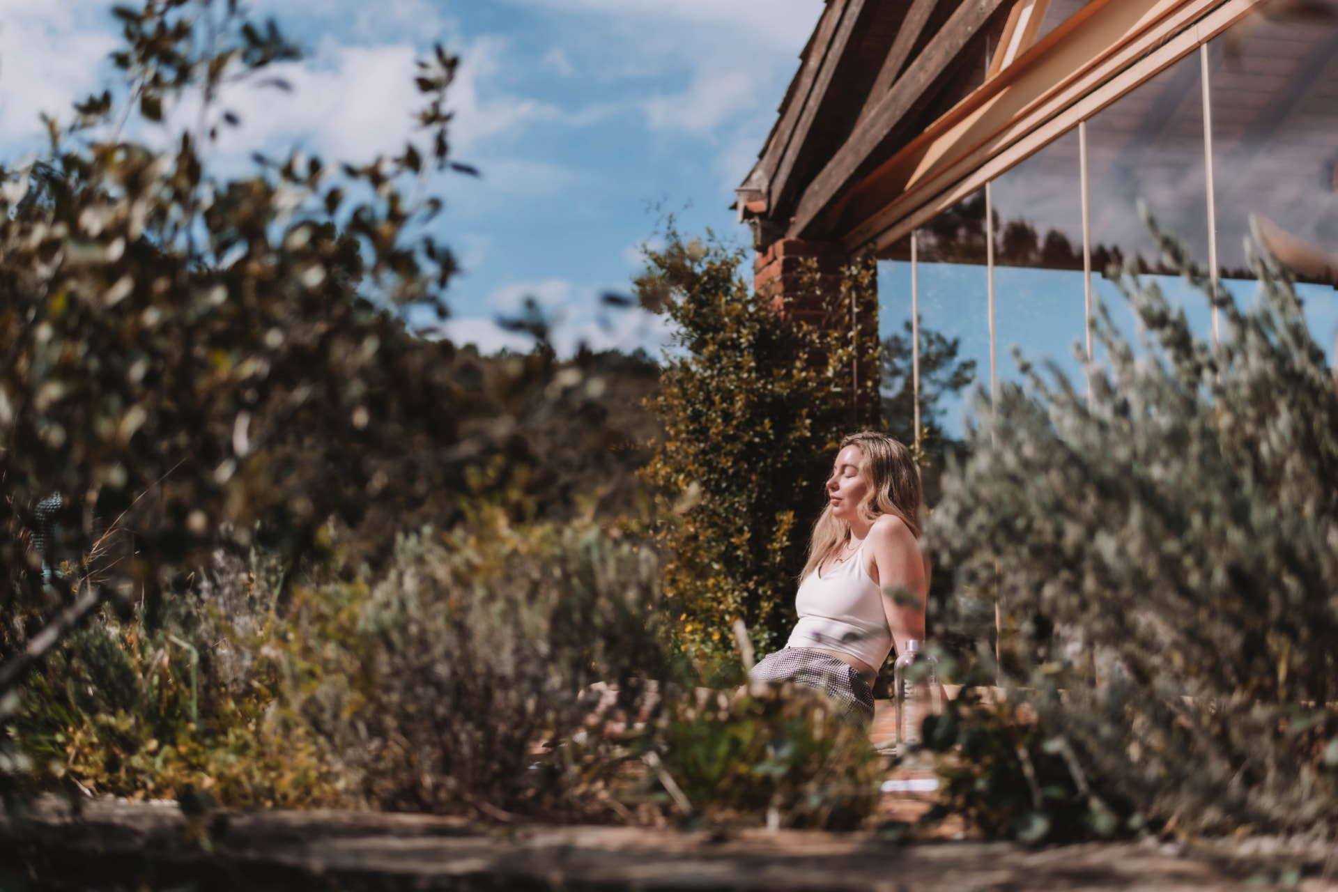 Woman resting in the sun in a wild garden beside the retreat house